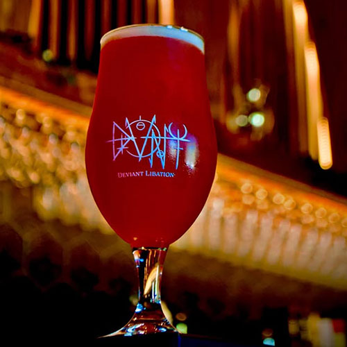 deviant libation beer in glass against dark bar in taproom